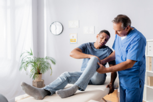 white chiropractor adjusting the knee of his black patient